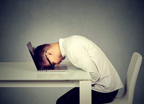 frustrated person resting his head on laptop